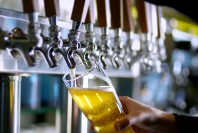 Tall glass with of beer being prepared to be served.