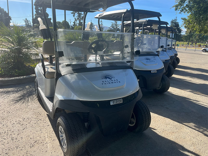 Row of Salinas Fairways golf carts parked and ready for play near the course.